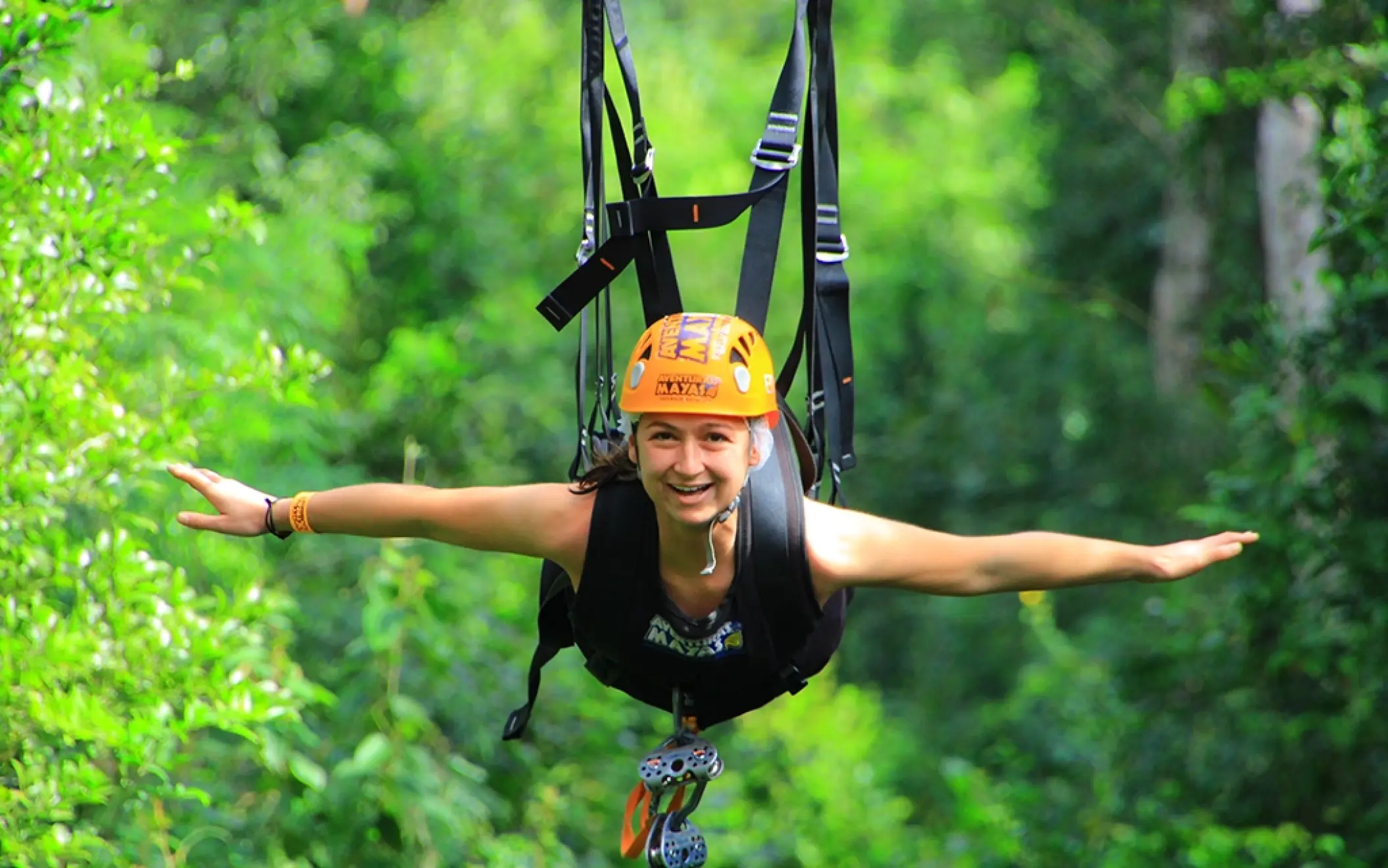 Person riding a zipline high above the jungle canopy as part of the Tulum Xtreme Tour