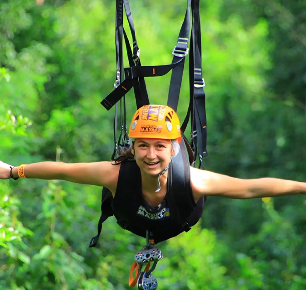 Person riding a zipline high above the jungle canopy as part of the Tulum Xtreme Tour