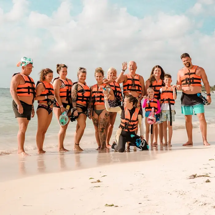 Akumal beach group: Large group of smiling people with snorkel gear and life vests on Akumal's sandy beach