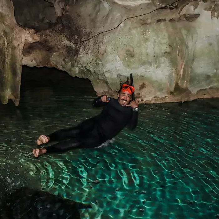 Cenote Yum Balam relaxing: Man floating on his back in the clear turquoise water of Cenote Yum Balam