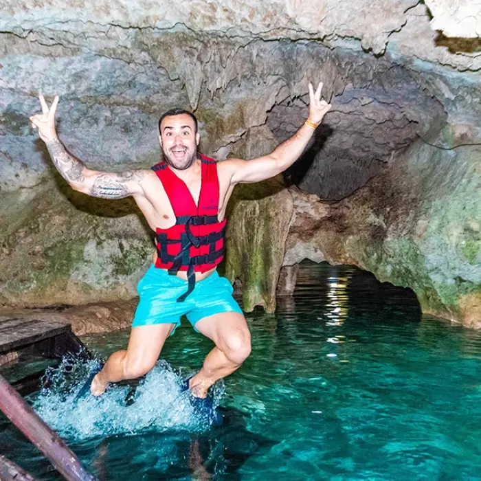 Cenote Yum Balam fun: Man excitedly jumping into the clear turquoise water of Cenote Yum Balam