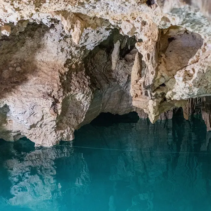 Turtle Cenote exploration: Still turquoise water inside a cavern with rock formations