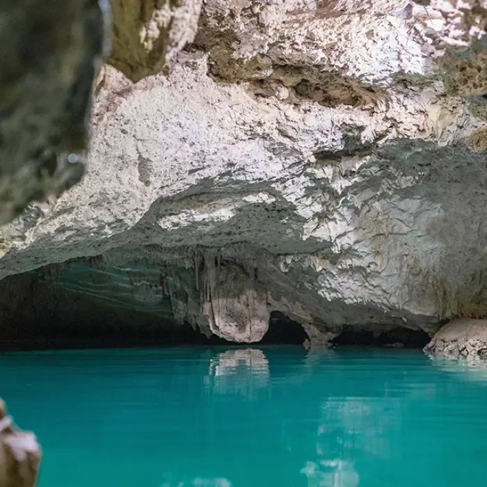 Turtle Cenote beauty: Clear turquoise water under a rocky cave ceiling with formations