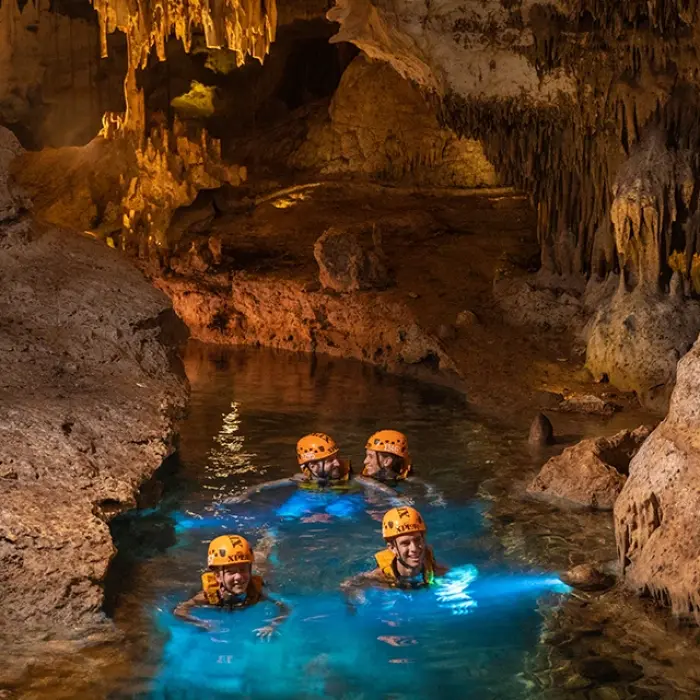 Group swimming in a glowing underground cave river
