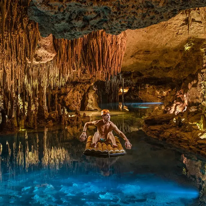Couple relaxing under stalactites in a magical underground cenote