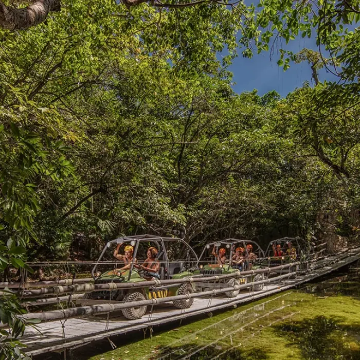 Xplor guests crossing a suspension bridge in jungle vehicles