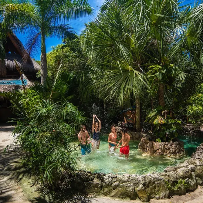 Family relaxing by a cenote in the jungle garden