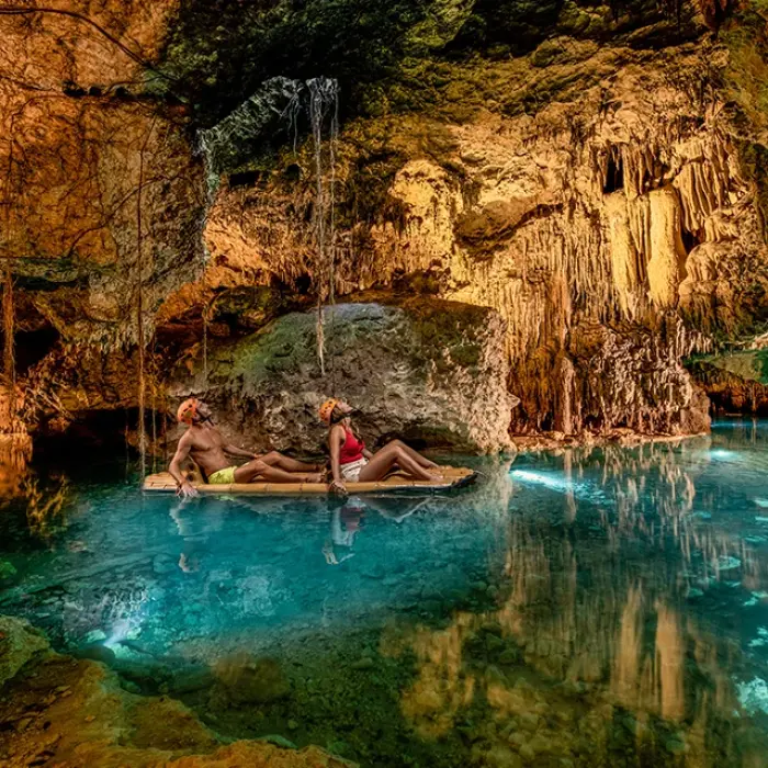 Friends celebrating with food and drinks by a jungle cenote