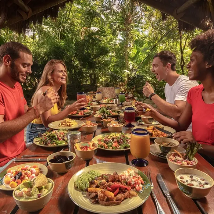 Friends toasting with tropical drinks during a jungle meal
