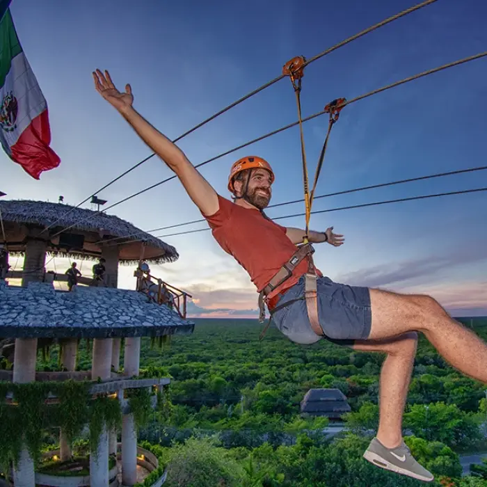 Man ziplining above the jungle waving to the camera