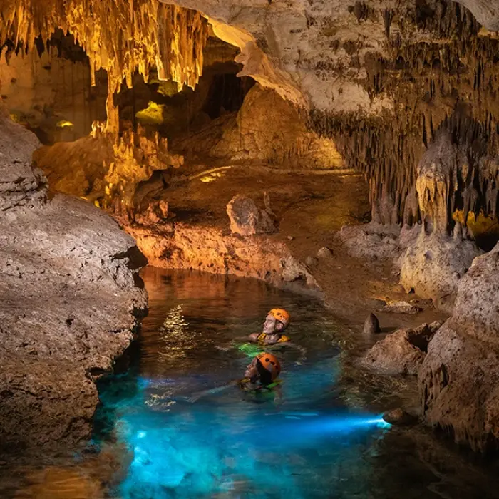 Solo adventurer floating in glowing cenote waters