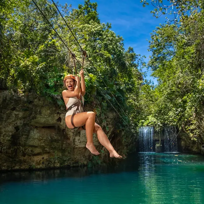 Woman ziplining into a stunning turquoise cenote