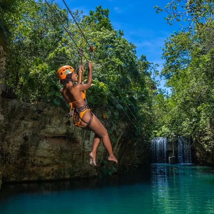 Woman ziplining into a stunning turquoise cenote