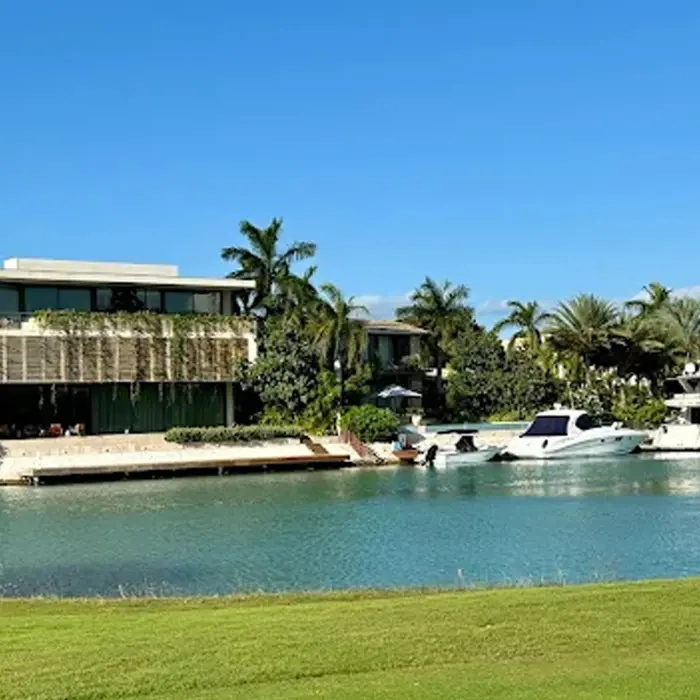 An aerial perspective of the signature island green connected by a wooden bridge, surrounded by bright blue marina waters and luxury condos