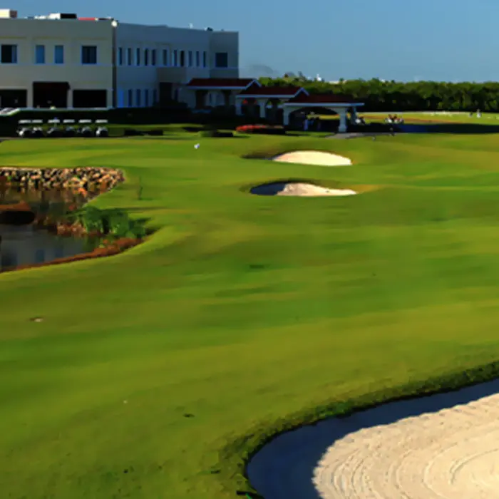 A scenic view of rolling fairways, sand bunkers, and a natural water hazard leading up to the elegant clubhouse at Moon Palace Golf Course.