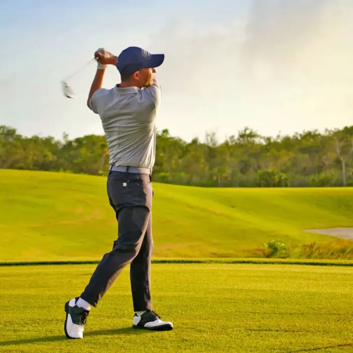 A male golfer captured in mid-swing on a vibrant green fairway during a beautiful golden hour at Moon Palace Golf Course.