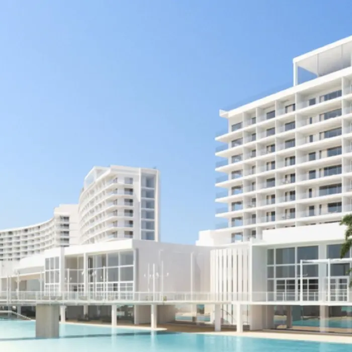 An architectural shot of the modern, white AVA Cancun resort buildings with a pool and palm trees.