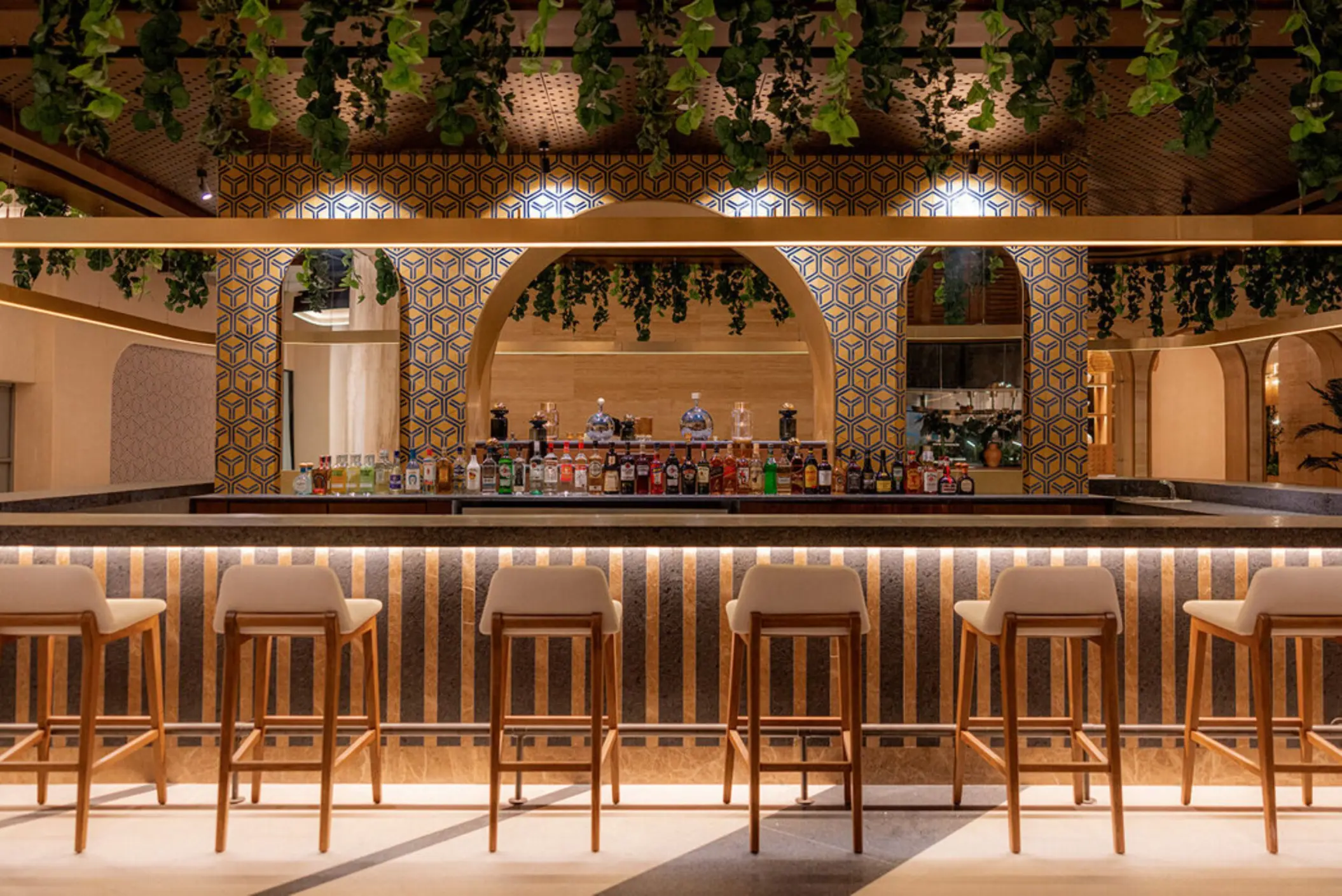 A modern bar at AVA Cancun resort featuring a geometric archway and hanging plants.