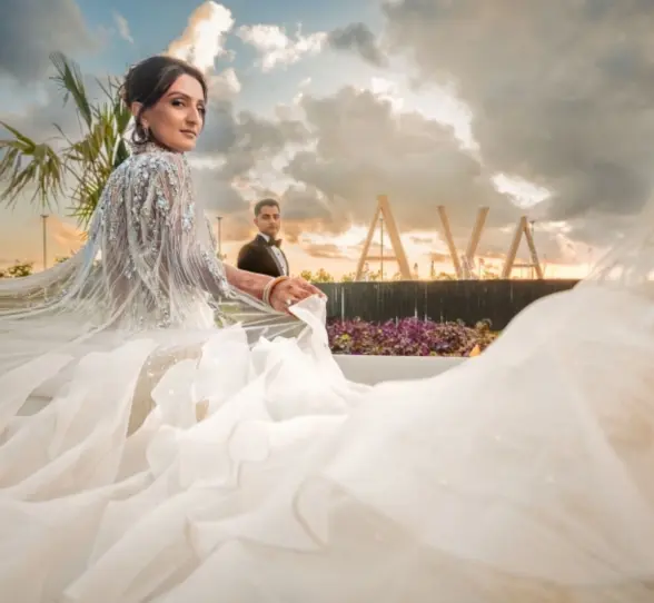 A bride and groom at AVA Cancun resort, with the bride's flowing dress in the foreground.