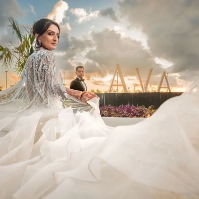 A bride and groom at AVA Cancun resort, with the bride's flowing dress in the foreground.