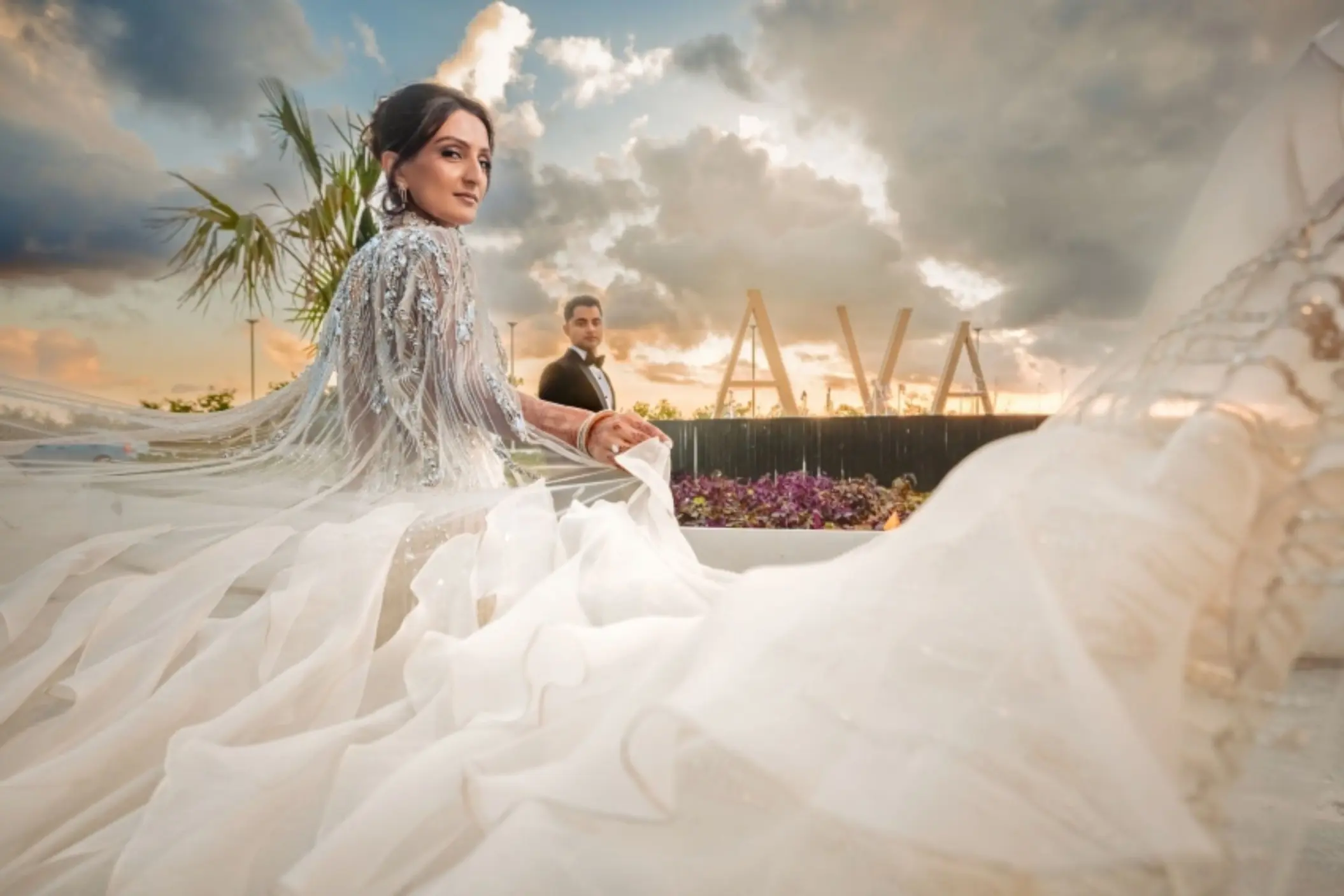 A bride and groom at AVA Cancun resort, with the bride's flowing dress in the foreground.