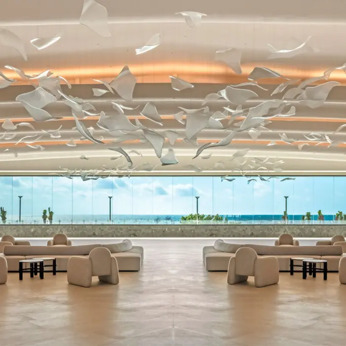 A grand, sunlit lobby with a stunning sculptural art piece and view of the ocean.