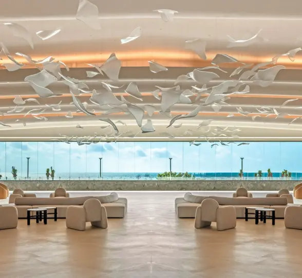 A grand, sunlit lobby with a stunning sculptural art piece and view of the ocean.