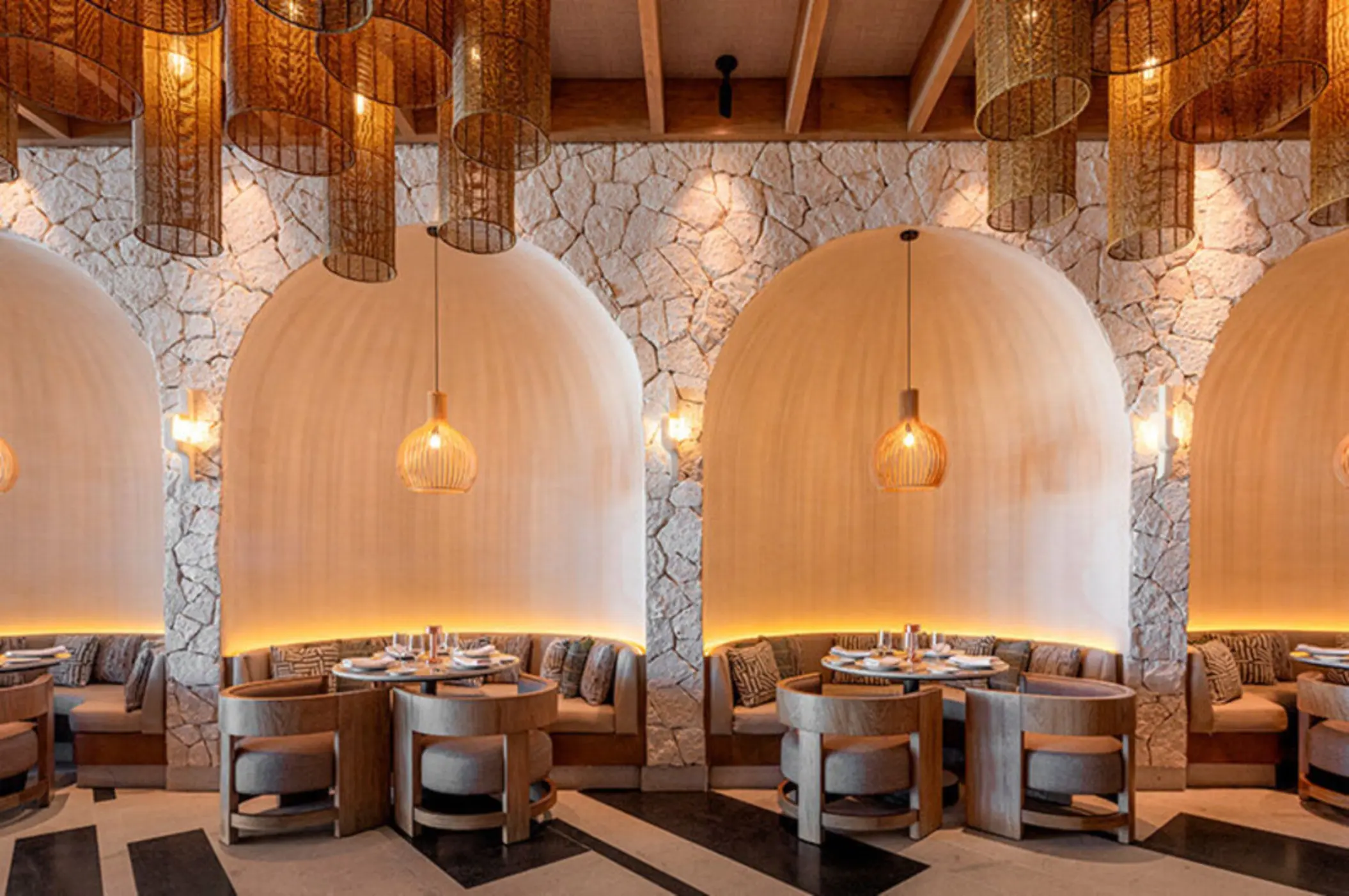 An elegant restaurant interior with unique dome-shaped seating alcoves and hanging wicker lamps.