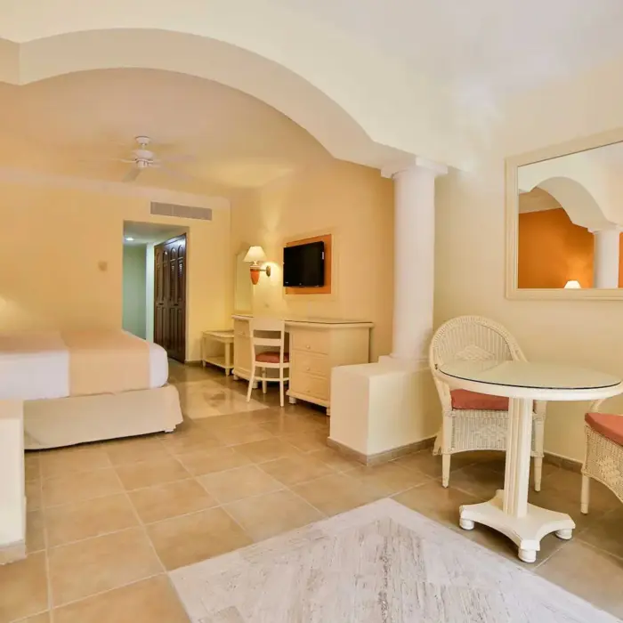 Bright and inviting suite with a comfortable bed, sitting area, and ample space at Bahia Principe Grand Coba.