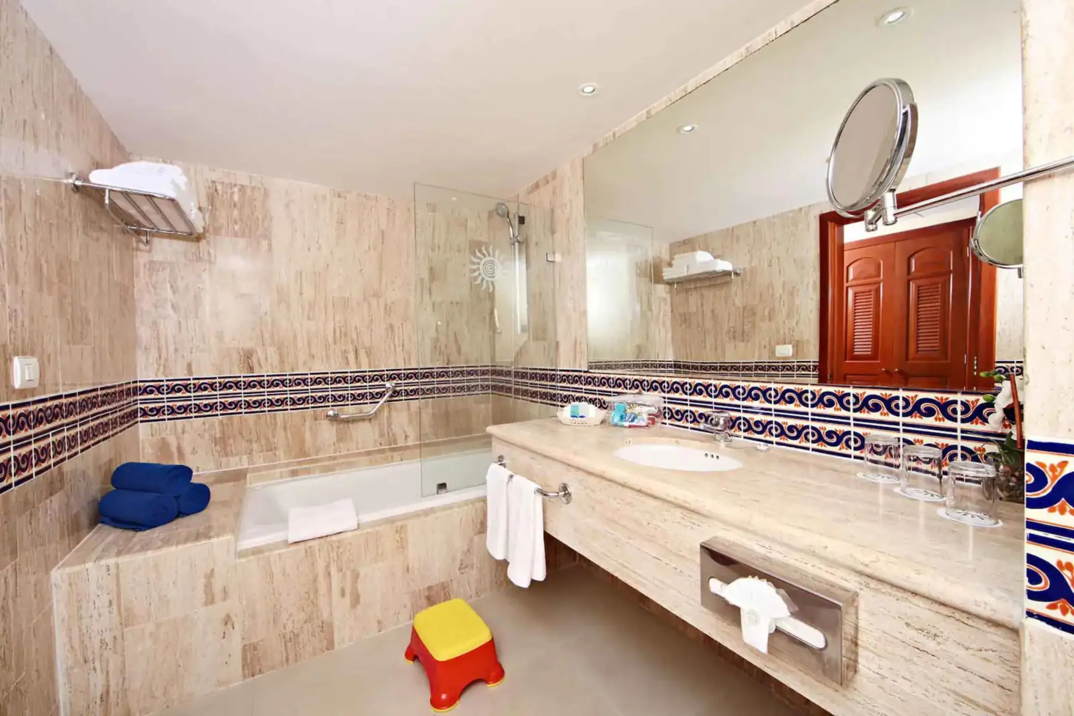 Bathroom with a large bathtub, vanity, and marble-like tiling in a suite at Bahia Principe Grand Coba.