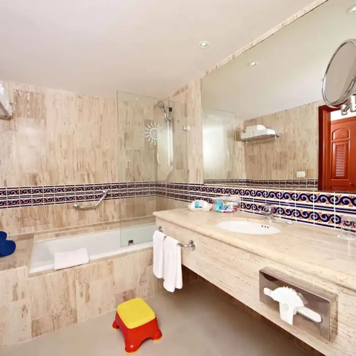 Bathroom with a large bathtub, vanity, and marble-like tiling in a suite at Bahia Principe Grand Coba.