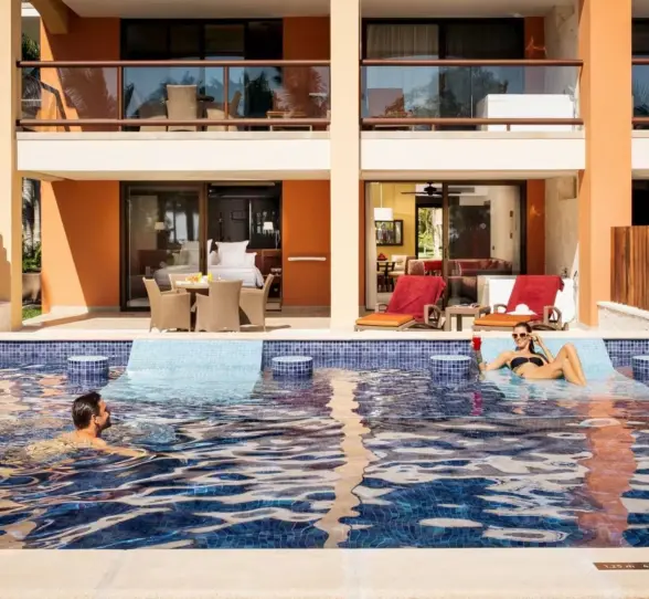 A couple relaxing in a swim-out pool directly accessible from their hotel suite balcony.