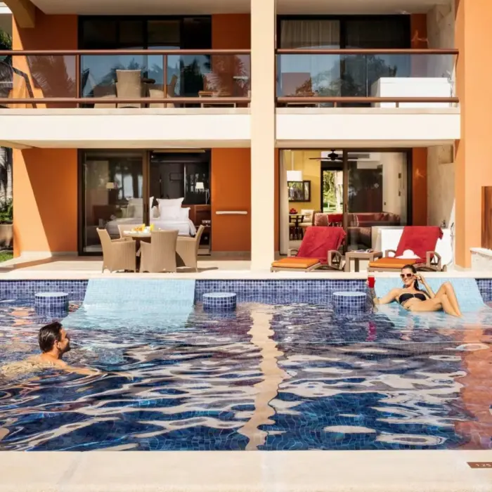 A couple relaxing in a swim-out pool directly accessible from their hotel suite balcony.