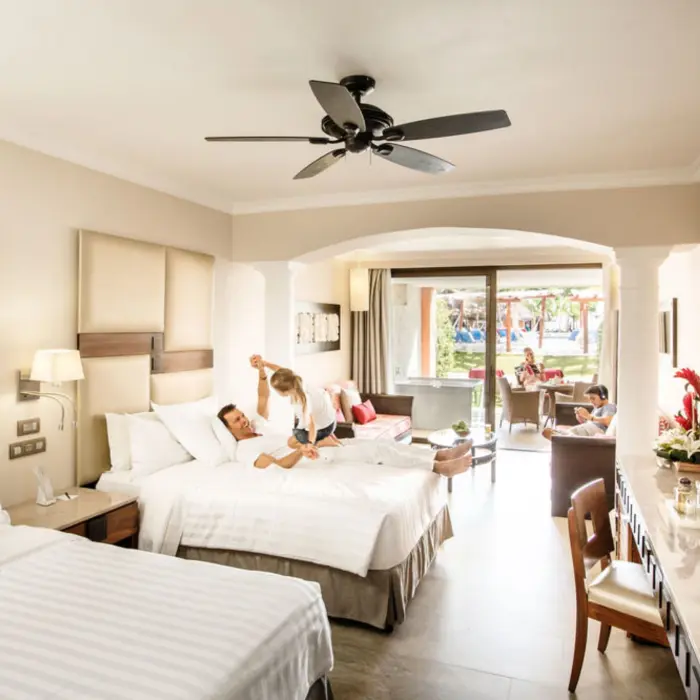 A family relaxing in a spacious hotel suite, with a comfortable bed and a sitting area.