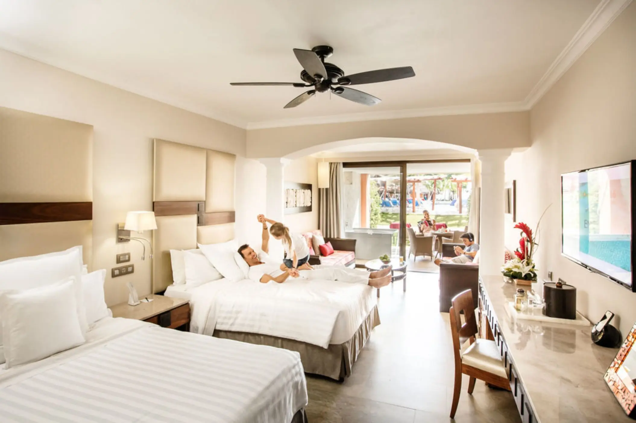 A family relaxing in a spacious hotel suite, with a comfortable bed and a sitting area.