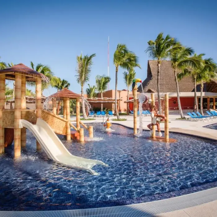 A vibrant kids' pool area with multiple water slides, shallow play areas, and palm trees.