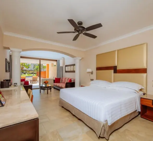 A well-appointed hotel suite featuring a comfortable king-size bed and a connected living area.