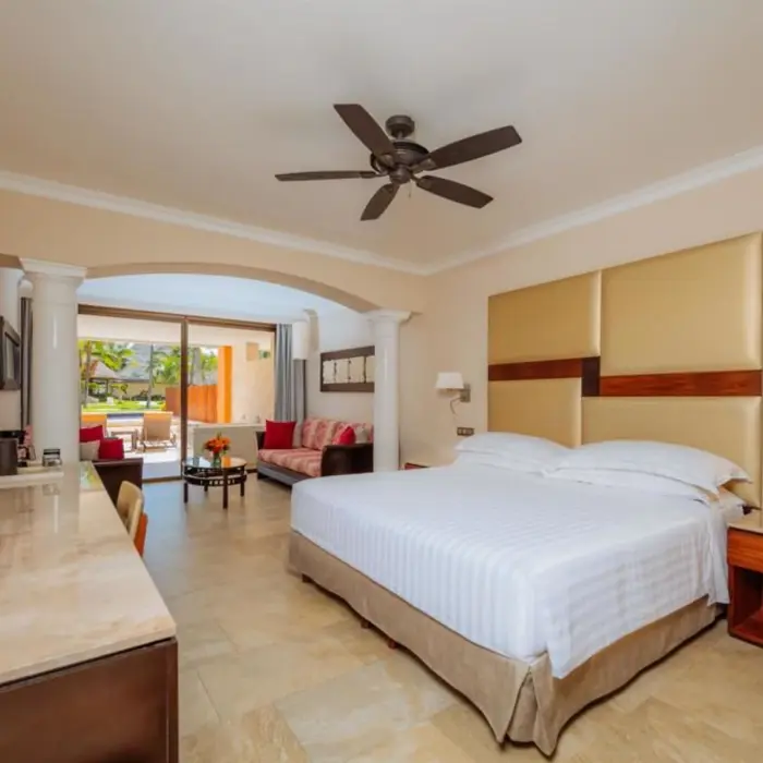 A well-appointed hotel suite featuring a comfortable king-size bed and a connected living area.