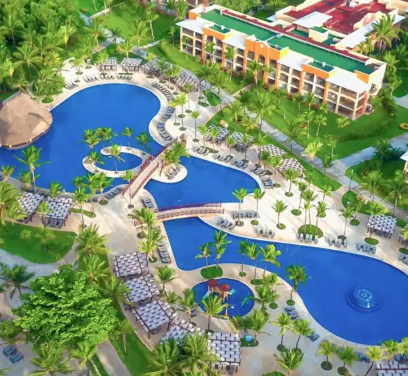 An aerial view showing the large, free-form swimming pools surrounded by palm trees and buildings.