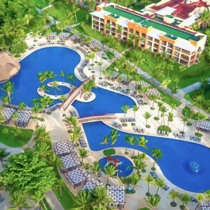An aerial view showing the large, free-form swimming pools surrounded by palm trees and buildings.