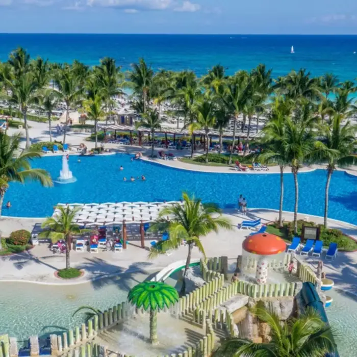 An aerial view of the resort with its large pools, kids' water park, and the beach in the background.