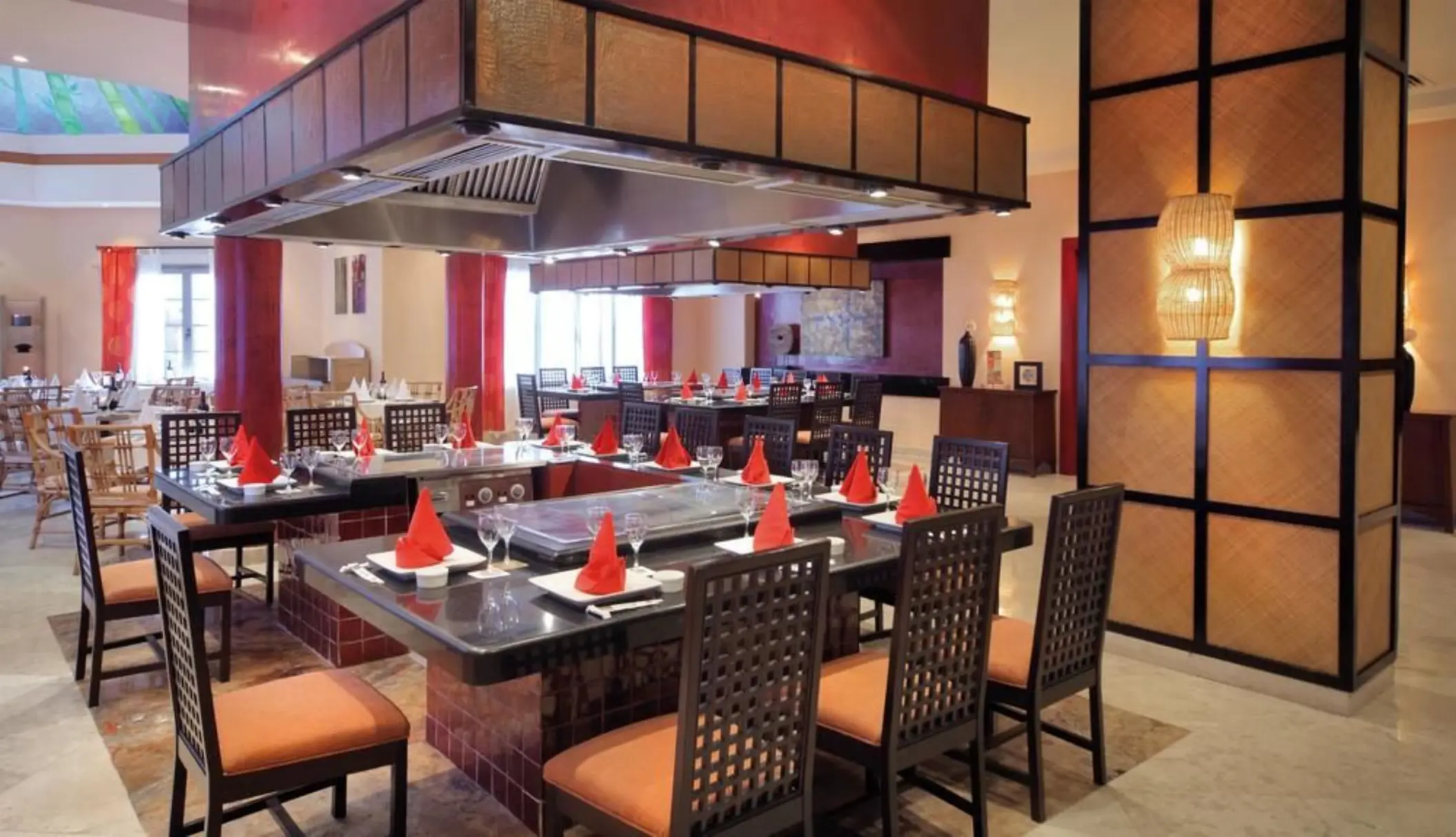 The interior of an elegant Asian restaurant with a teppanyaki grill station and neatly set tables.