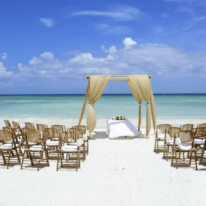 A romantic beach wedding setup with an altar and rows of chairs on the white sand.