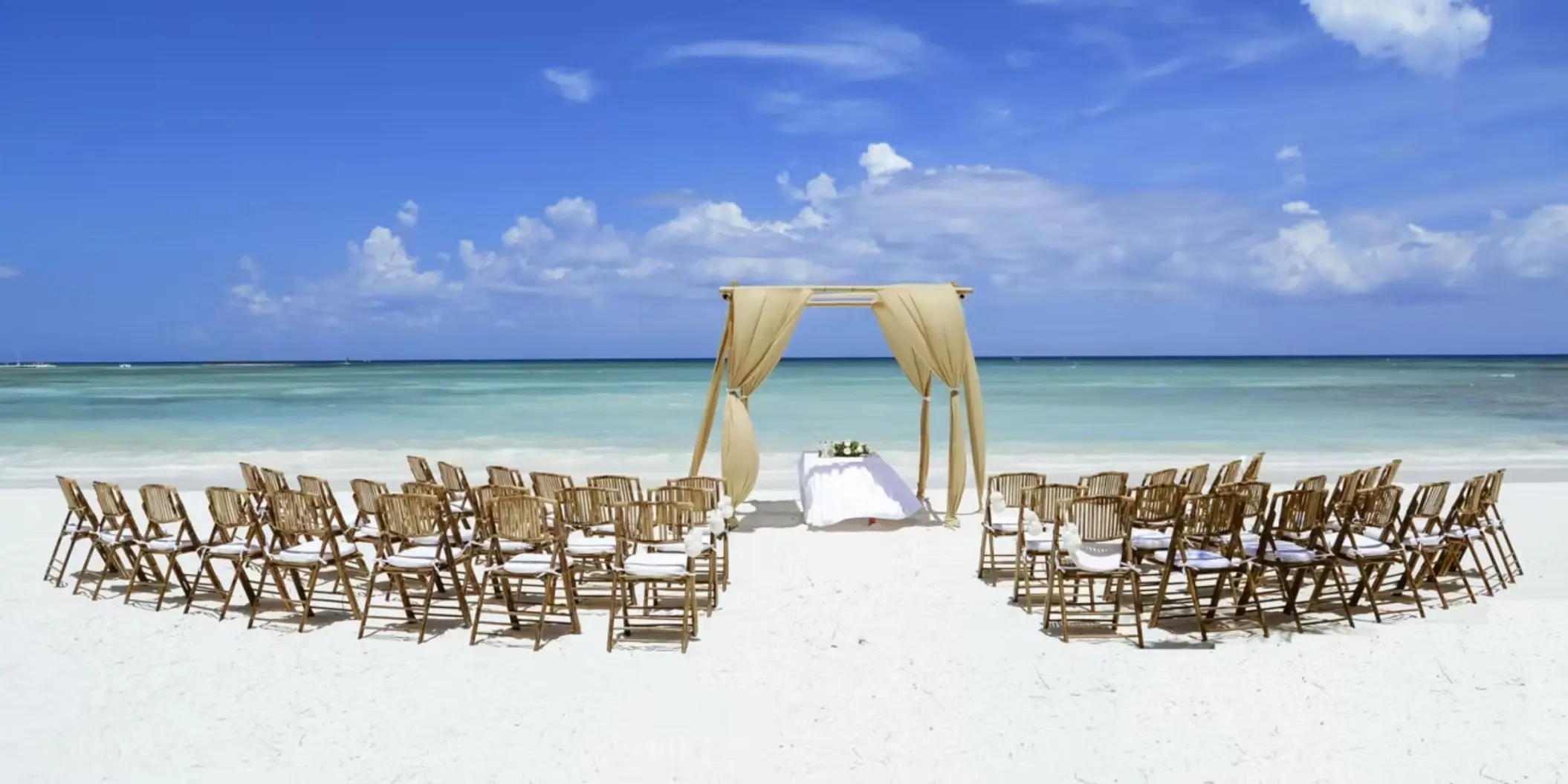 A romantic beach wedding setup with an altar and rows of chairs on the white sand.
