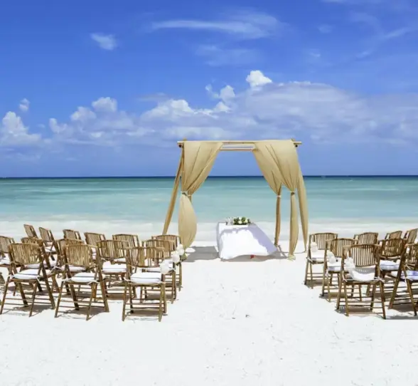 A romantic beach wedding setup with an altar and rows of chairs on the white sand.