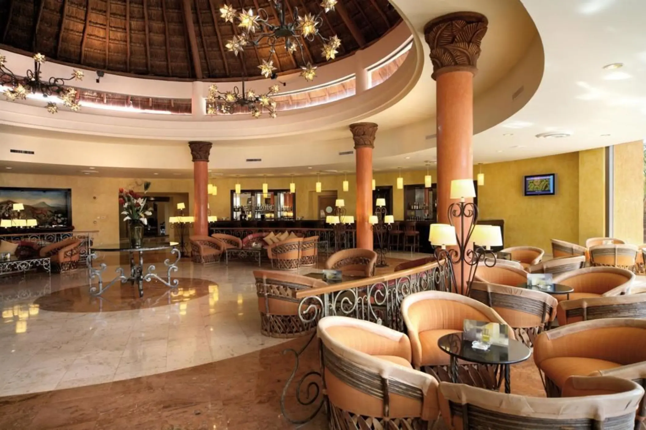 A circular lobby bar area with comfortable seating and a thatched roof, creating a tropical atmosphere.