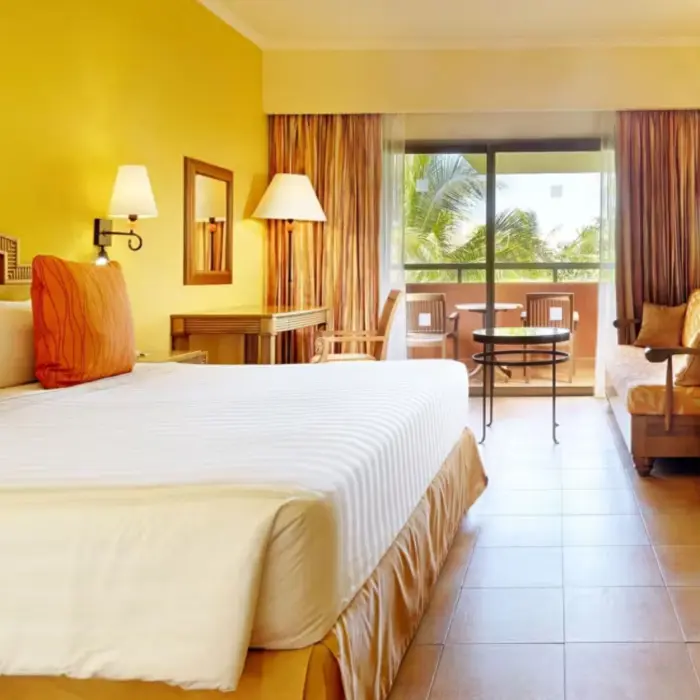 A cozy hotel room with a king-sized bed, a sofa, and a private balcony with outdoor furniture.