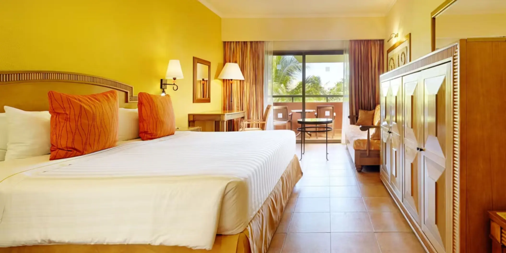 A cozy hotel room with a king-sized bed, a sofa, and a private balcony with outdoor furniture.