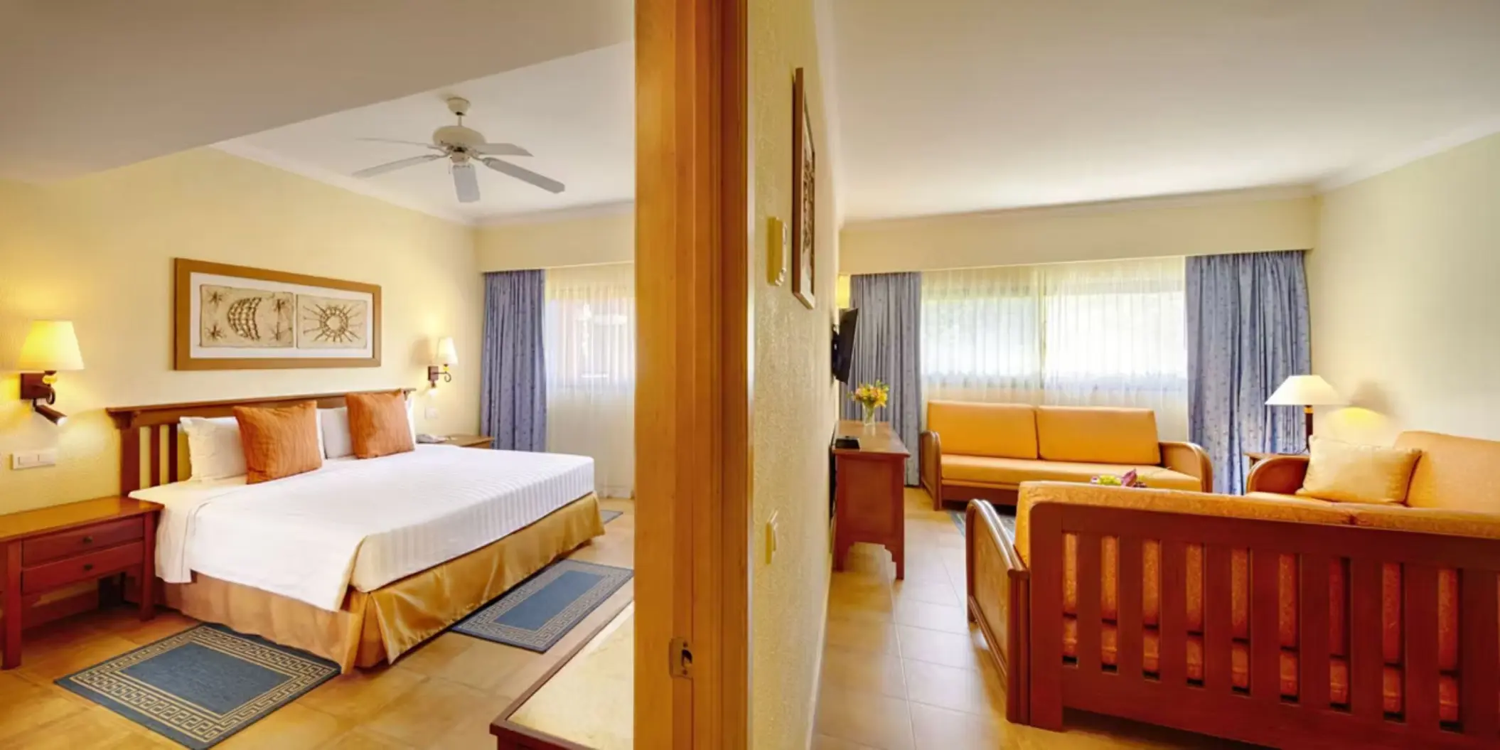 A spacious suite with a king-sized bed and a separate living room area with a sofa and television.