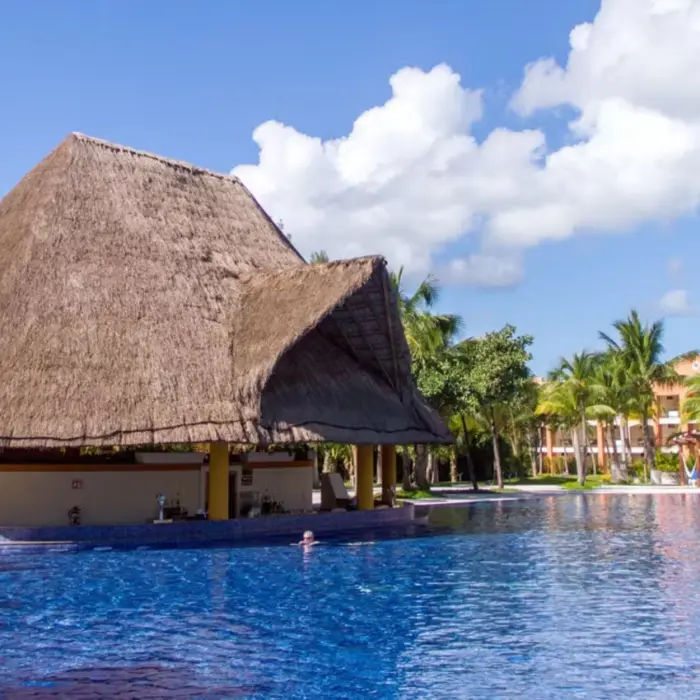 A rustic thatched-roof swim-up bar located in the middle of a large, inviting swimming pool.